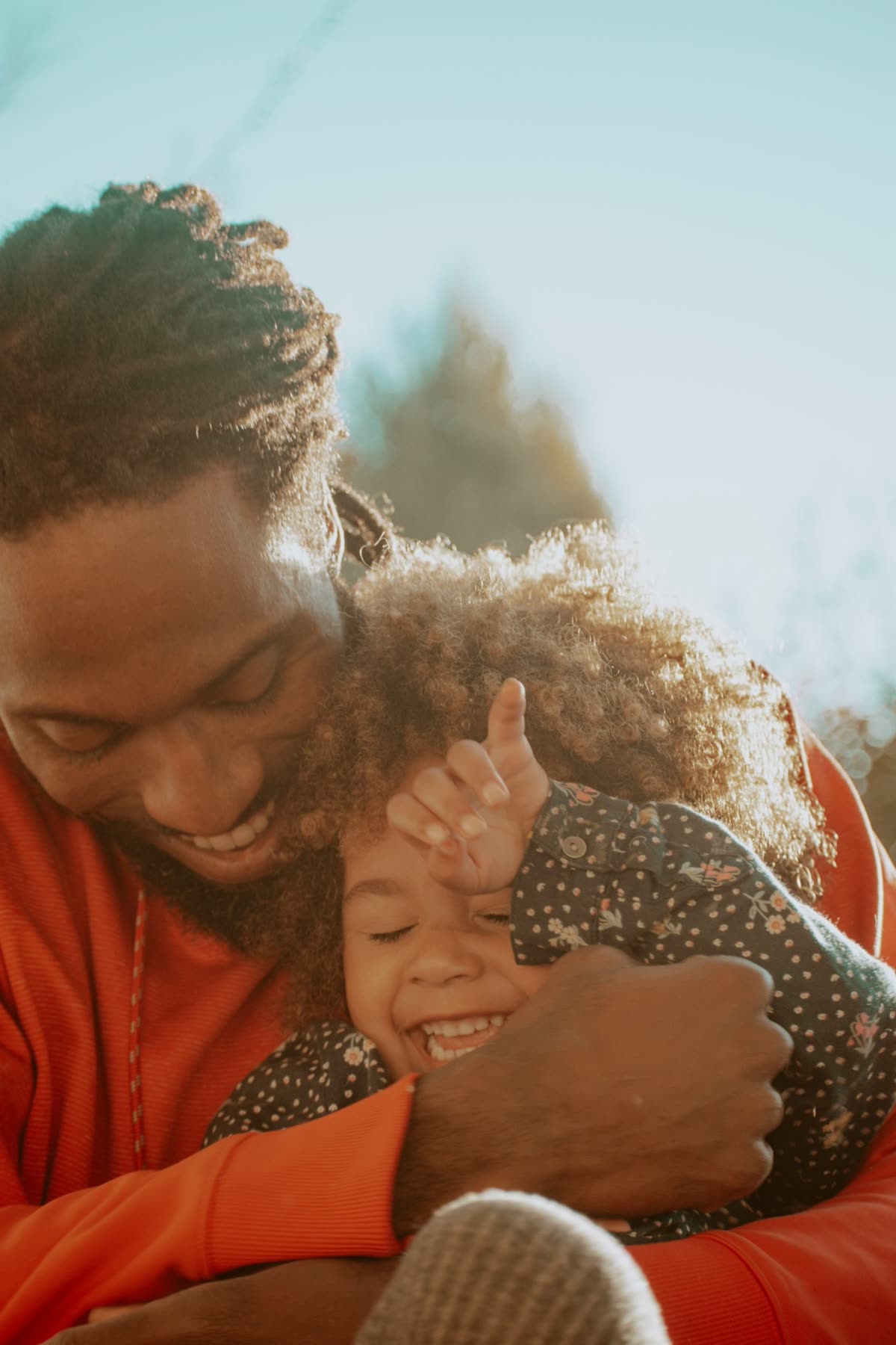 A father hugs his laughing young daughter