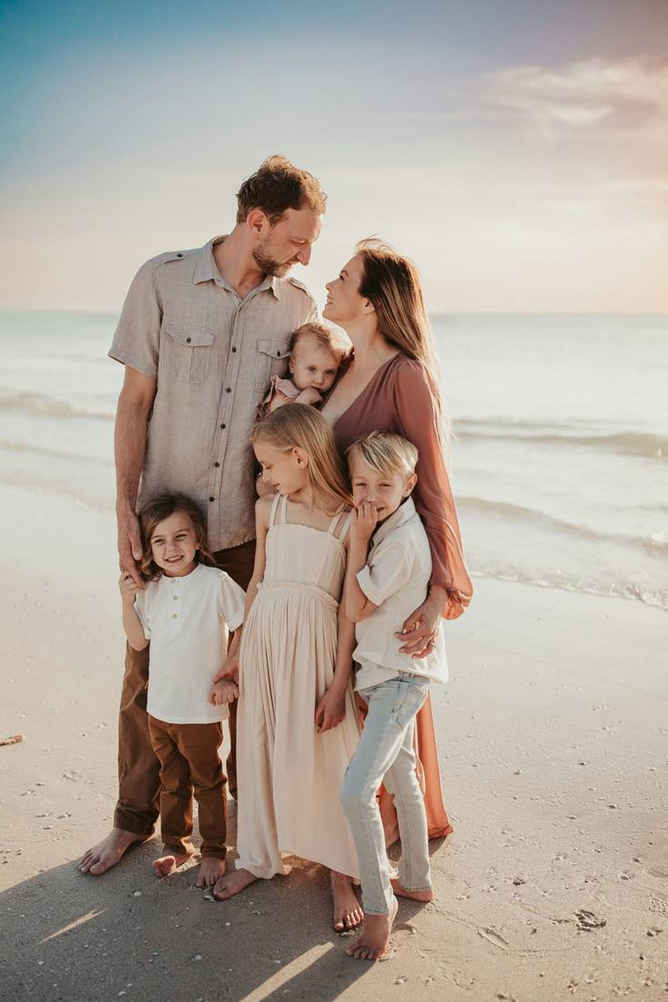 A family with four kids embracing on the beach at sunset